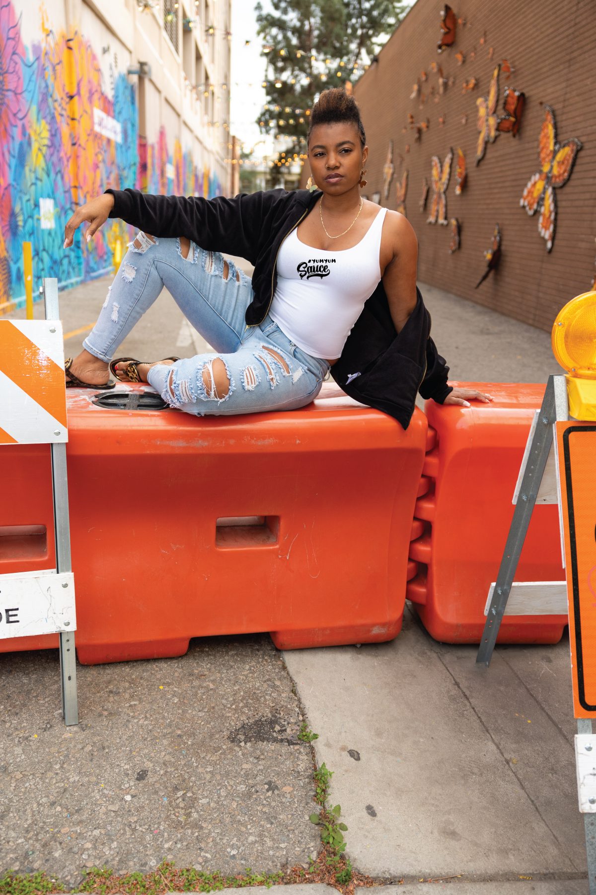 A woman sitting on top of orange barriers.