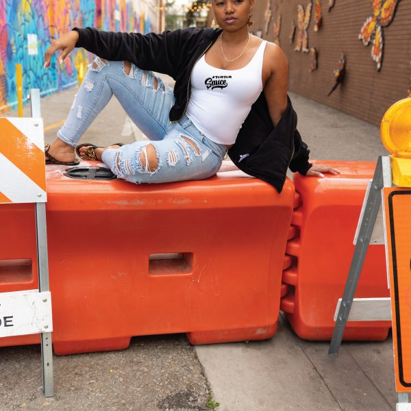 A woman sitting on top of orange barriers.